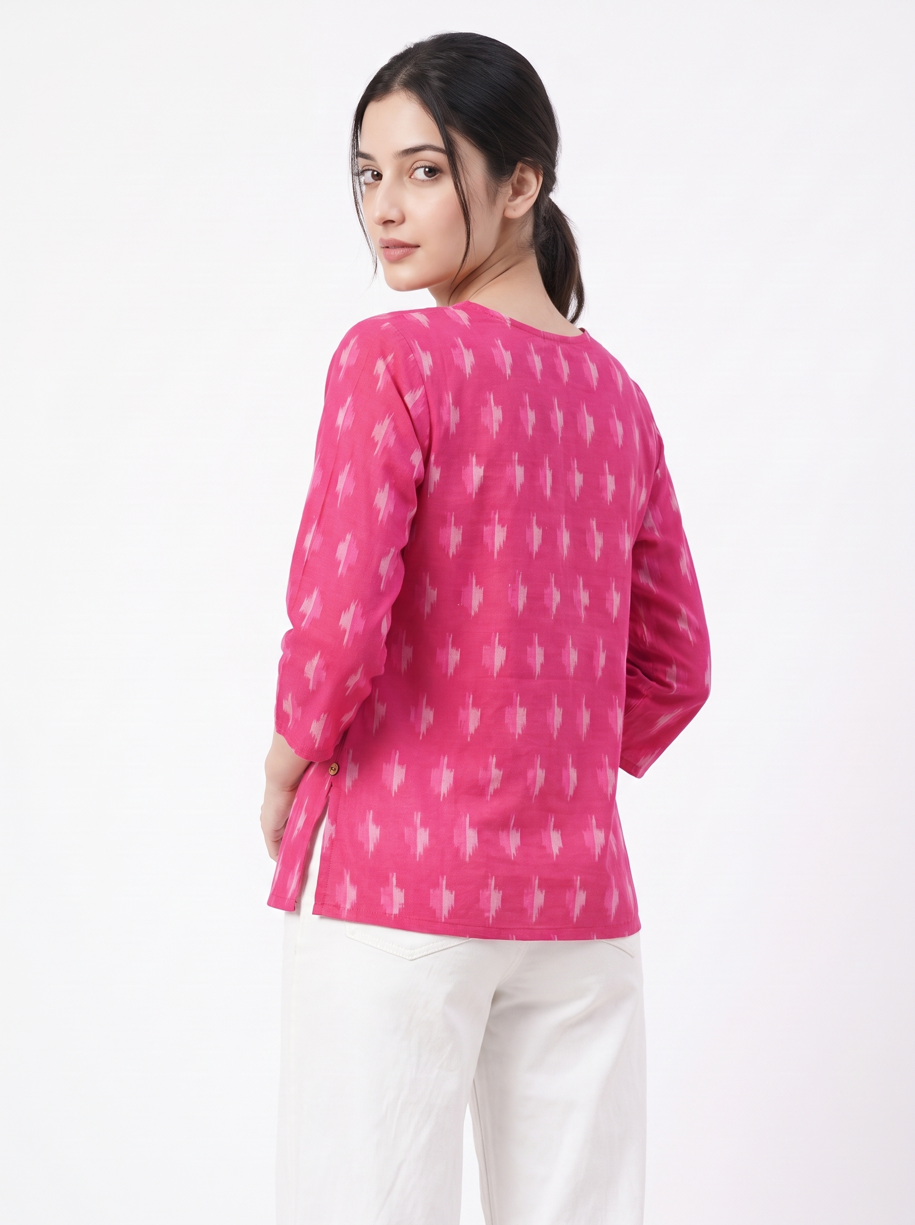 A woman wearing a bright pink long-sleeve kurta with a white ikat pattern, shown from the back against a plain white background.