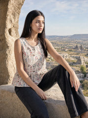 A graceful beige sleeveless top featuring delicate multicolor botanical motifs in soft red, blue, green, and earthy tones