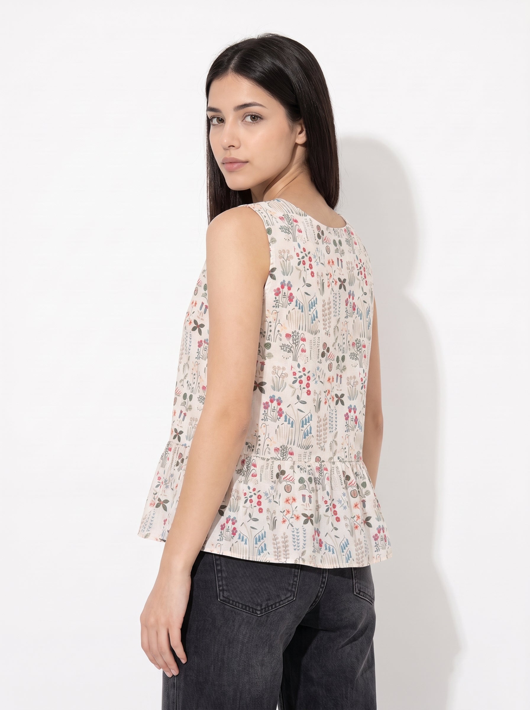 A graceful beige sleeveless top featuring delicate multicolor botanical motifs in soft red, blue, green, and earthy tones