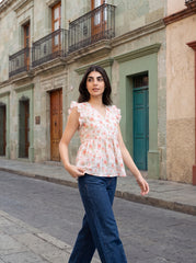 A fresh off-white top featuring soft peach floral motifs with subtle green botanical accents for a feminine everyday look.