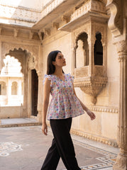 A fresh off-white top featuring soft pink, blue, peach, and green floral motifs for a bright feminine look.