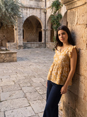 A cheerful mustard yellow top featuring elegant white floral motifs for a bright and feminine look.