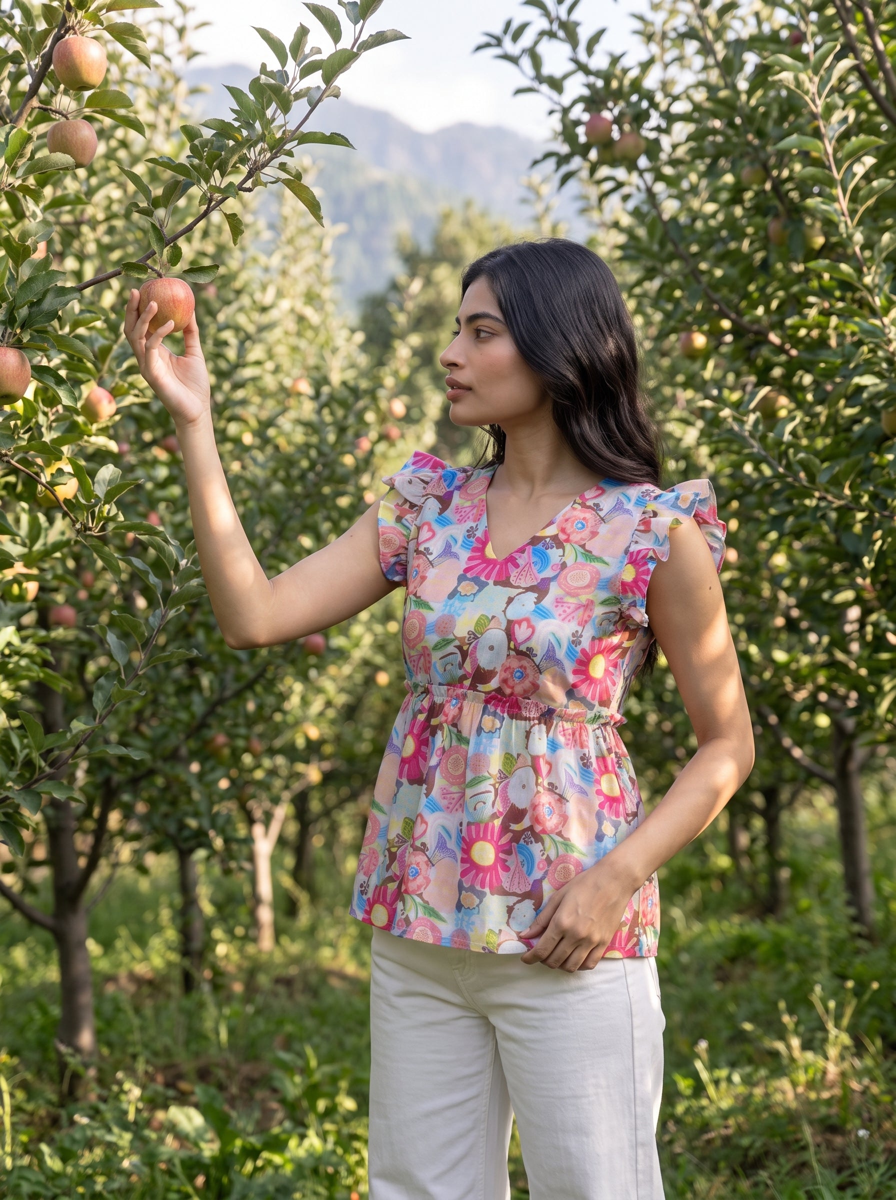 A lively off-white top featuring bright pink, blue, green, peach, and yellow floral motifs for a cheerful statement look. The V-neckline and layered ruffle sleeves add a playful feminine touch, while the gathered peplum waist creates a flattering, flowy silhouette.