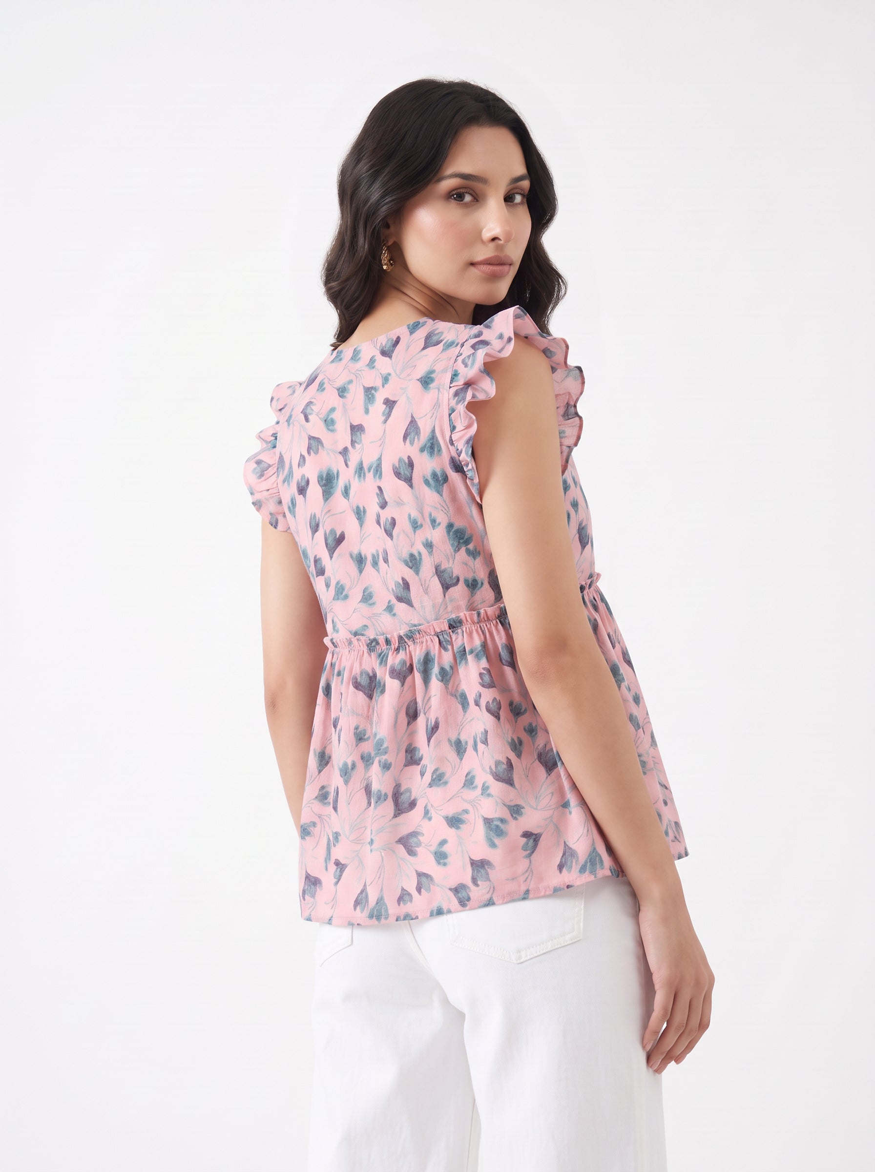 A soft pink top featuring elegant dark teal floral and leafy motifs for a fresh, feminine look. The V-neckline and layered ruffle sleeves add a graceful touch, while the gathered peplum waist creates a flattering, flowy silhouette.