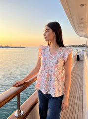 A fresh off-white top featuring soft peach florals with green and blue botanical accents for a charming feminine look. 